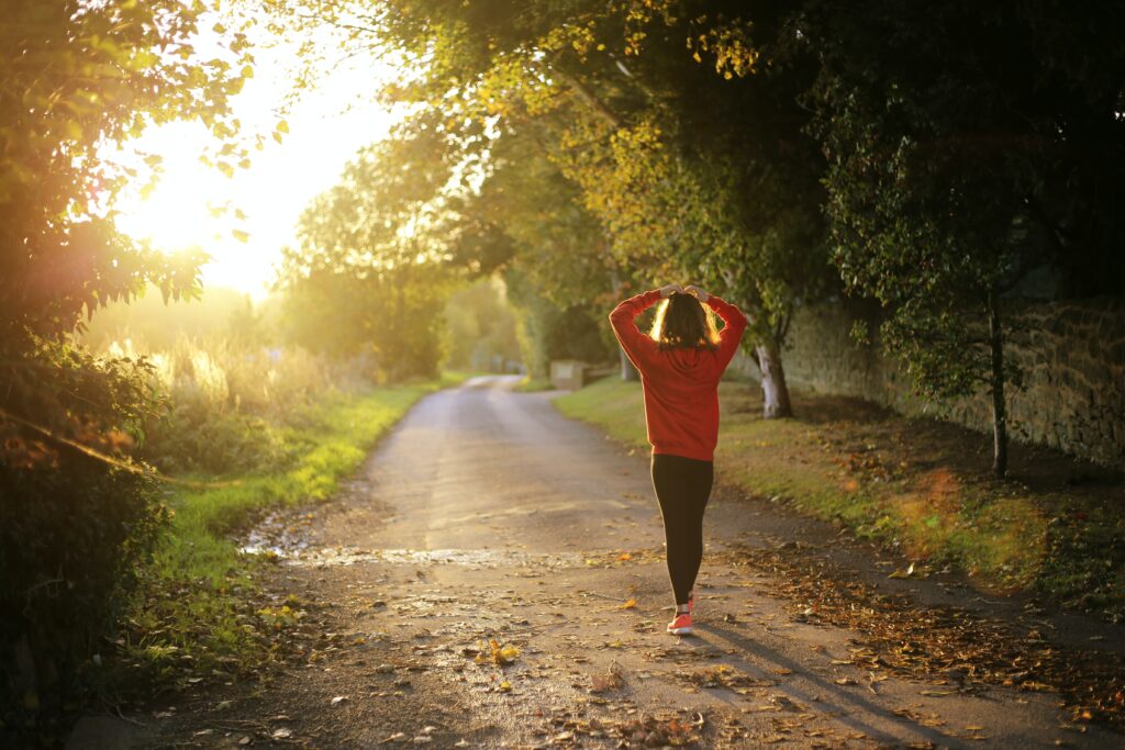 Person walking down a sunlight path holding their head