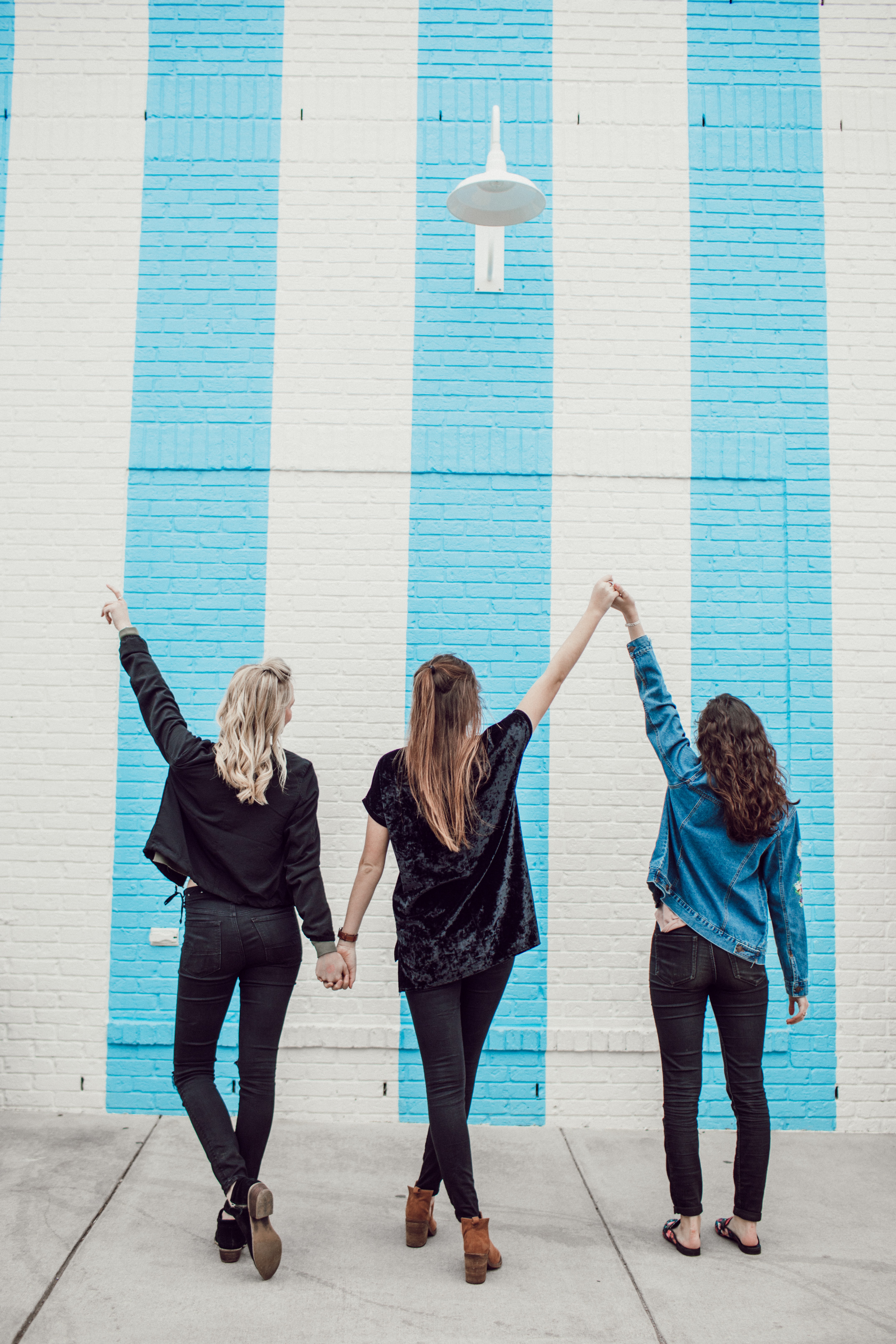 friends holding hands looking at a wall